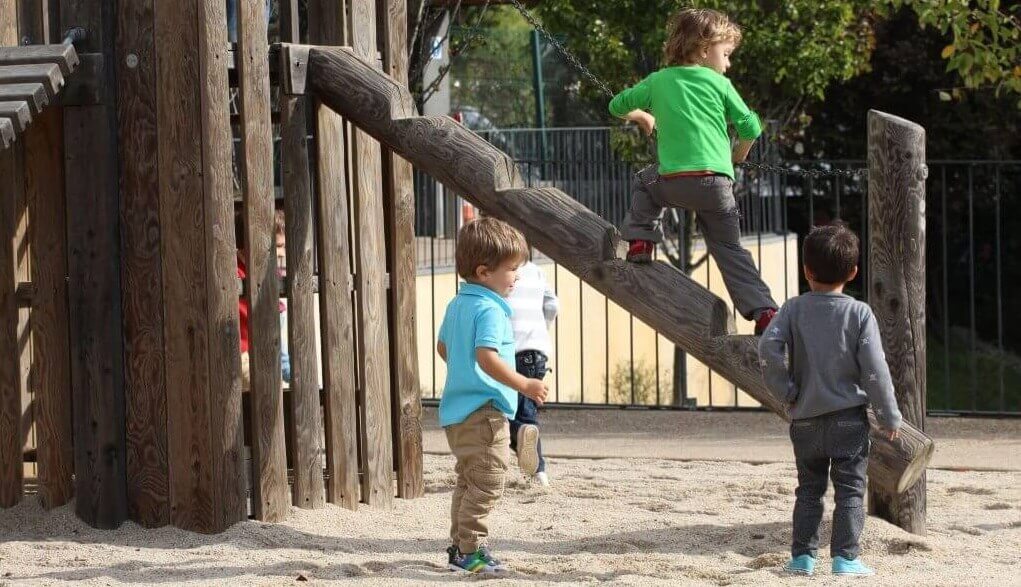 Preschool children playing on a wooden playground structure