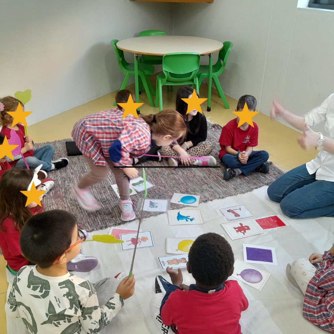 Preschool children participate in an educational activity involving flashcards and fly swatters.