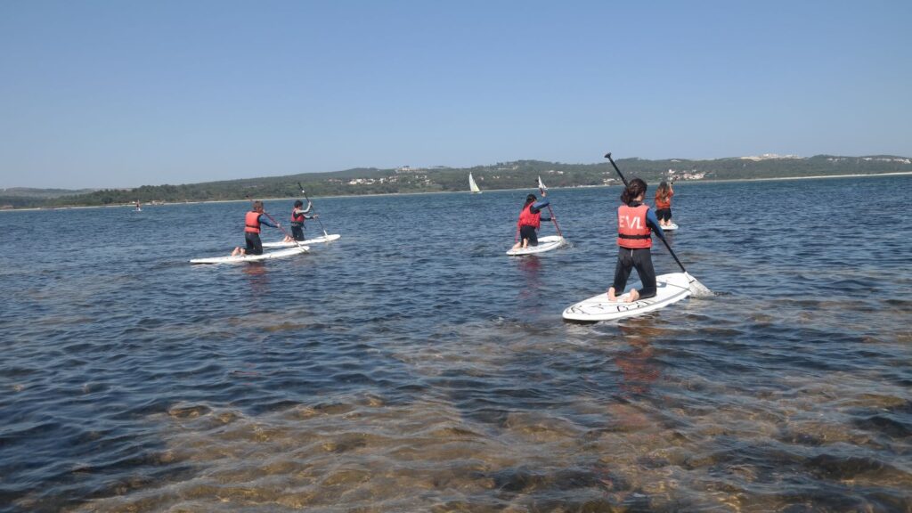 Students paddleboarding on a calm lake during a school activity
