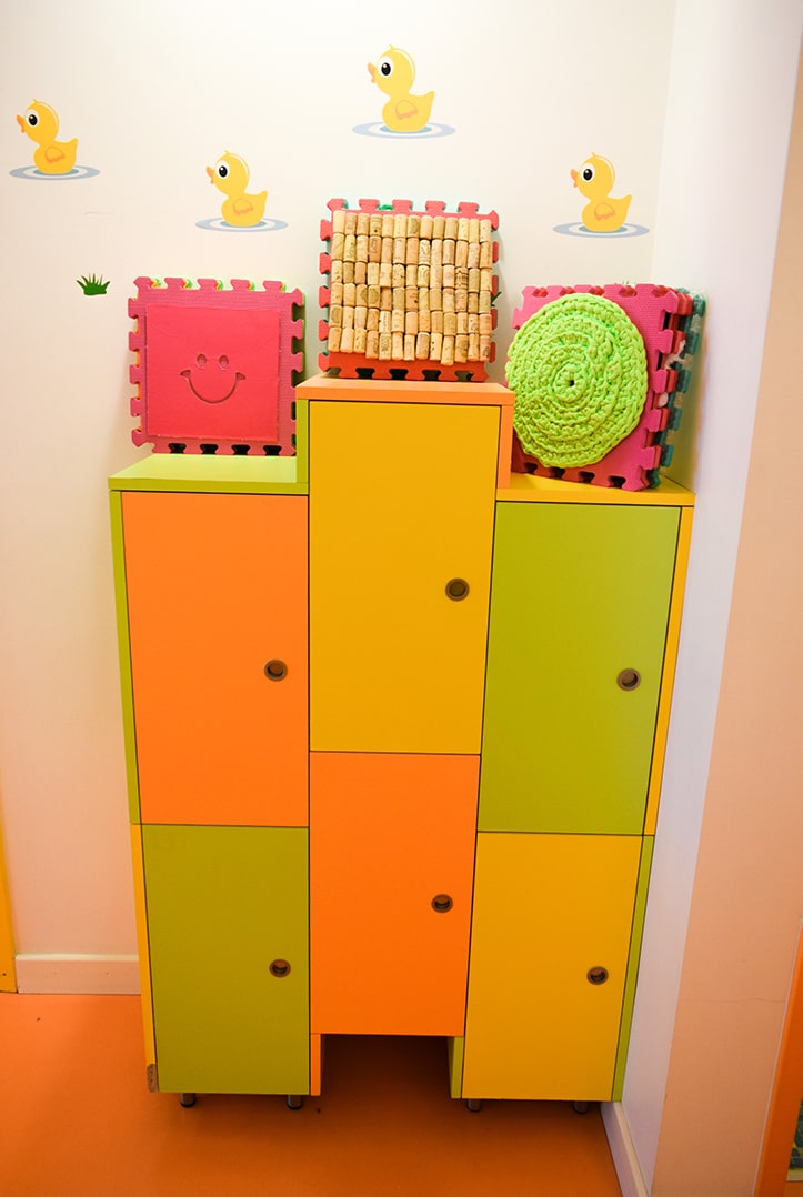 Colorful storage cabinet with cork and crocheted decorations in a preschool classroom