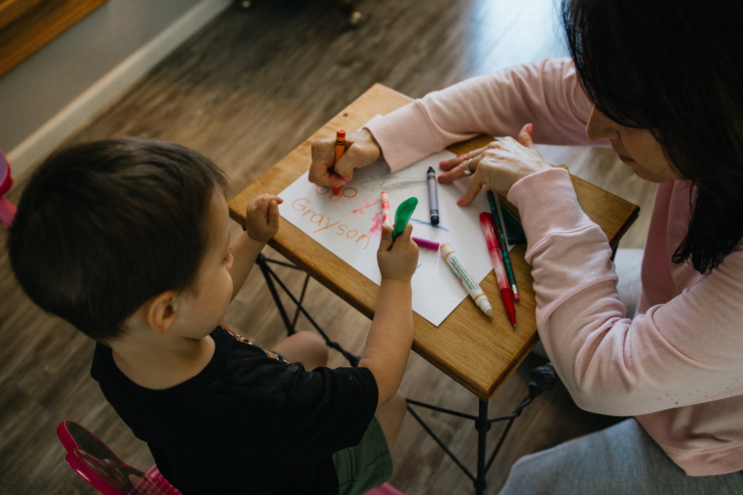 Preschool teacher assisting a child with coloring