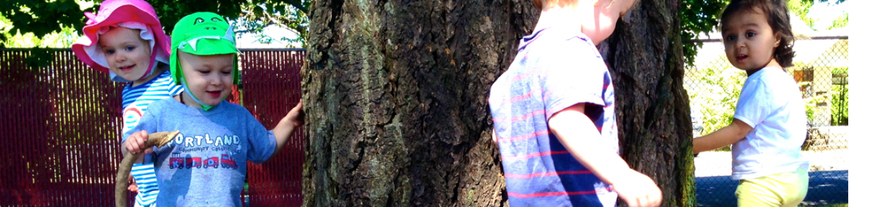 Preschool children playing outdoors near a tree