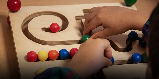 Child playing with a wooden marble run toy