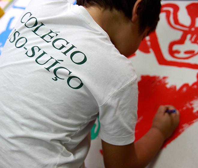 Student wearing a Colégio Luso-Suíço shirt participates in an art class